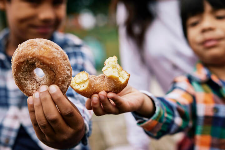 Children holding fresh apple cider donuts at Weber’s Cider Mill Farm in Parkville