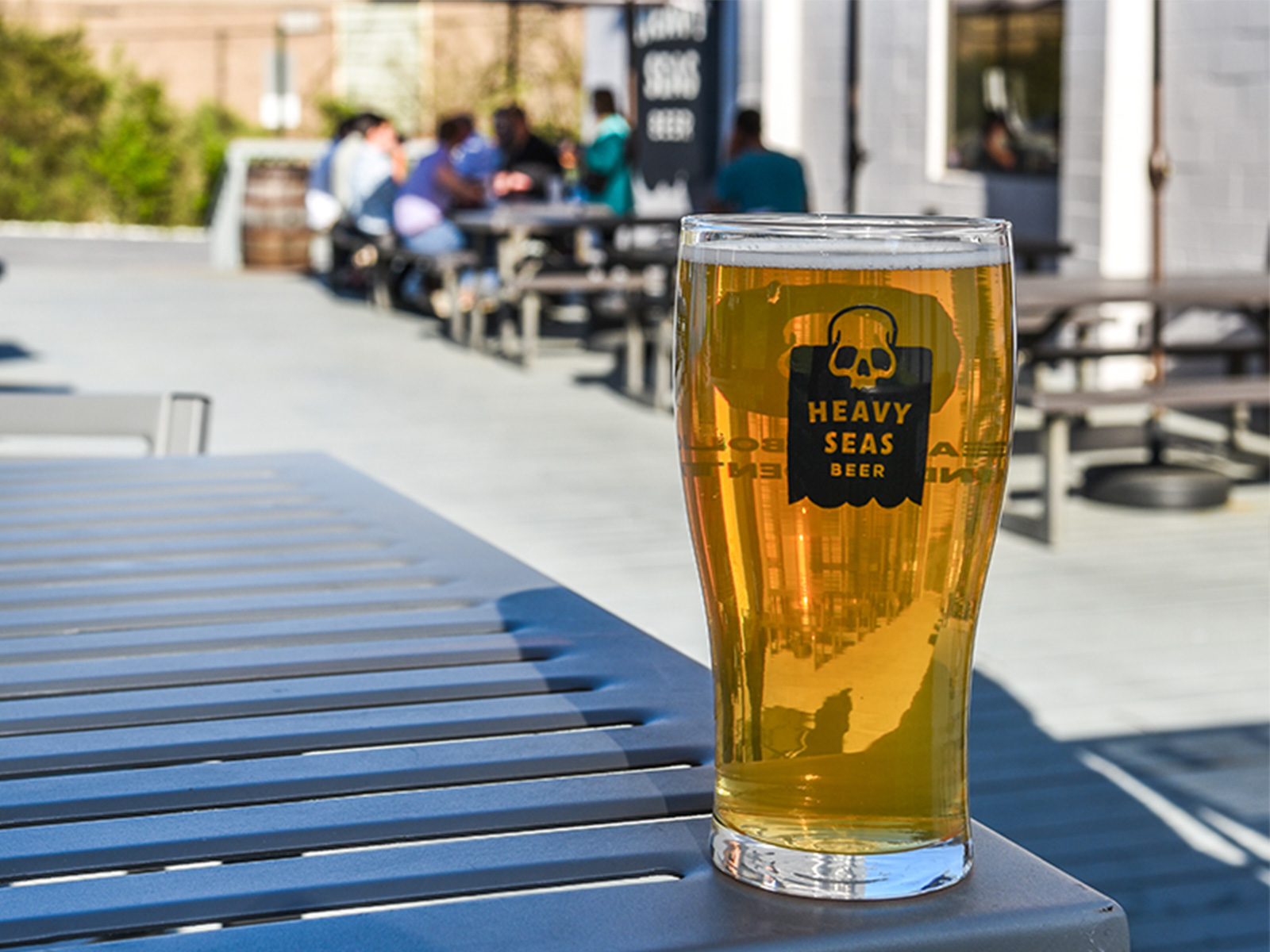 Pint of golden craft beer in a Heavy Seas branded glass on an outdoor patio in Baltimore County, Maryland.