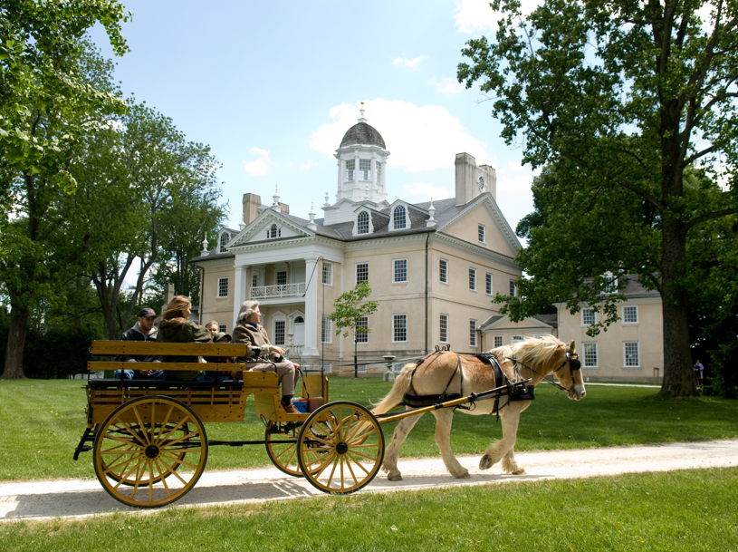 A horse and carriage strolling on a walkway in front of an old mansion in Baltimore County.